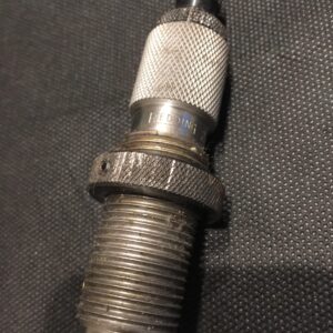 Close-up of a worn spark plug on a dark surface.